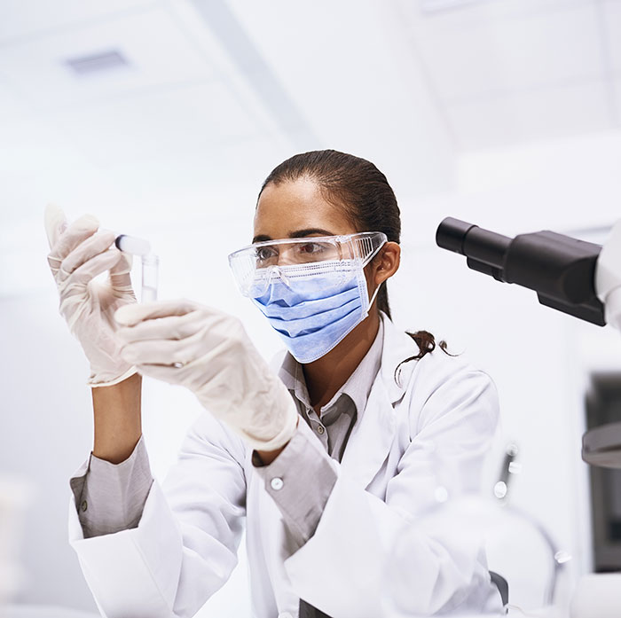 African-American female doctor working with vials next to telescope