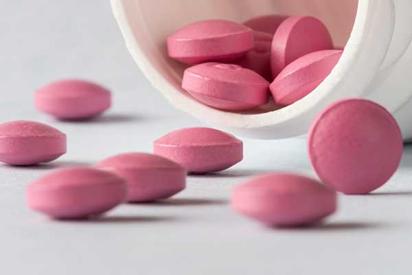 Photo of pink pills spilling out of their container